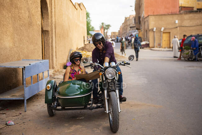 Couple d'aventuriers moto à la recherche sur la carte — Photo de stock