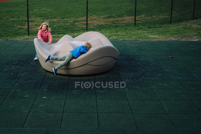 Deux enfants jouent sur un manège dans une aire de jeux. — Photo de stock