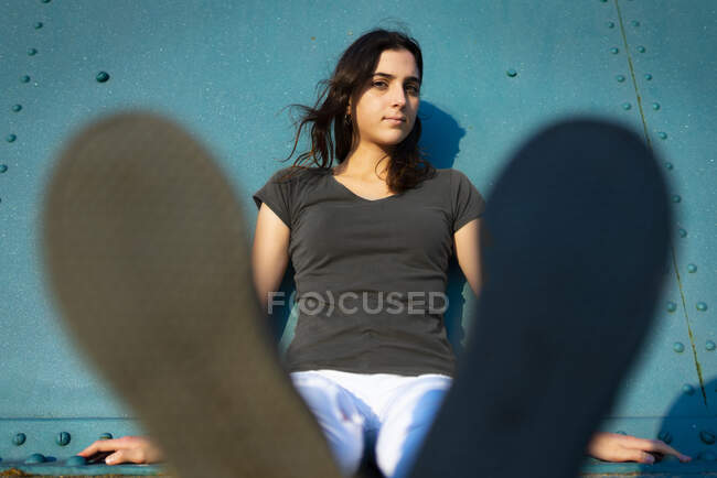 Portrait d'une fille assise dans la rue avec un mur bleu — Photo de stock