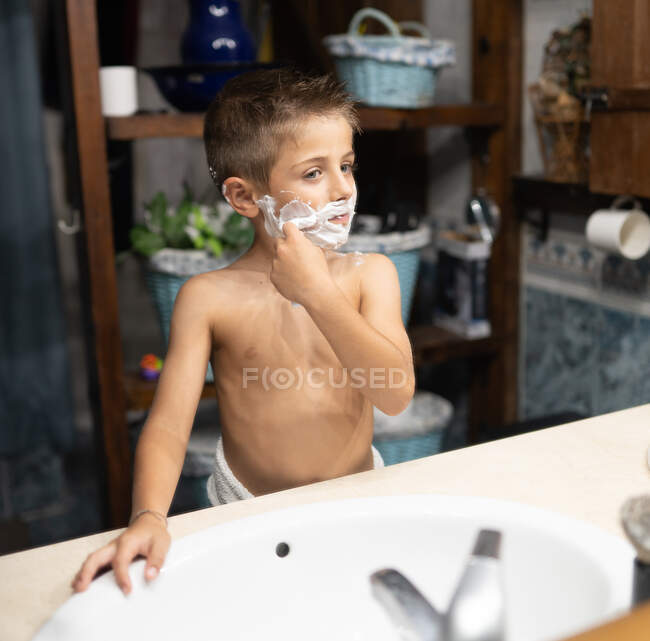 Pequeno menino barbear como um adulto no banheiro na frente do espelho — Fotografia de Stock