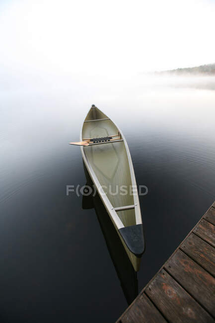 Ein schnittiges Kanu, das an einem Steg auf einem ruhigen Teich in Maine festgemacht ist. — Stockfoto