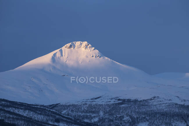 Primera luz brillando sobre la cumbre de Fugltinden, Troms, Noruega - foto de stock