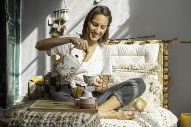 Дівчина готує чай традиційним способом на дивані свого будинку — стокове фото