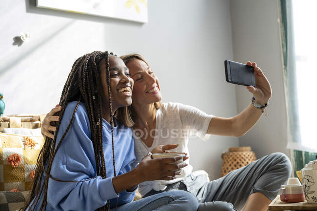 Pareja de amigos tomando una selfie o videollamada en casa - foto de stock