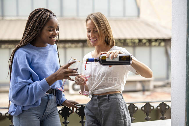 Couple of friends drinking wine on the balcony — Stock Photo