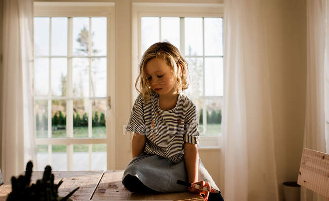 Jovem menina sentou-se desenho em casa com caneta no rosto — Fotografia de Stock