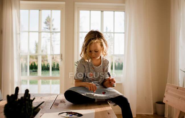 Chica joven dibujando en su mano y cara en casa - foto de stock
