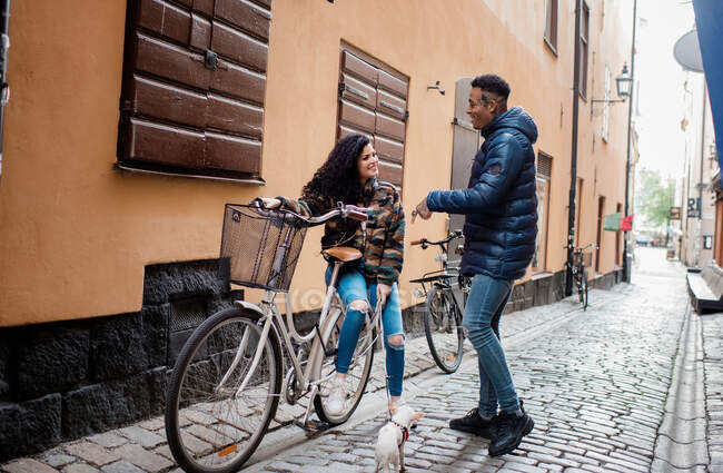 Homme et femme dans la rue en Europe assis en train de parler sur un vélo push — Photo de stock