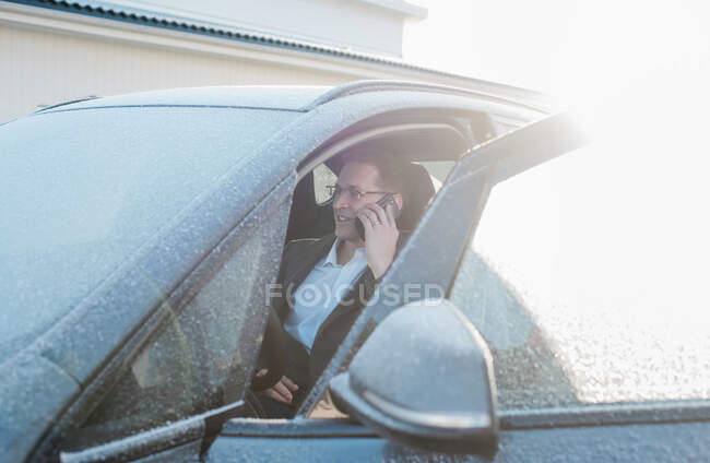 Чоловік сидів у морозній машині, розмовляючи по телефону, йдучи на роботу — стокове фото