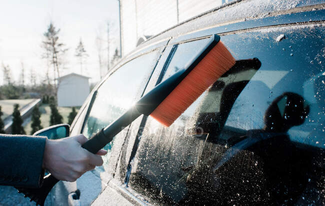 Mans mano spazzolando il gelo lontano dalla sua auto al mattino — Foto stock