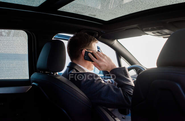 Businessman talking on the phone in his frosty car at home — Stock Photo