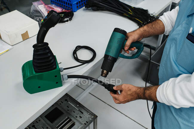 Homem com pistola de ar quente reparando uma chave de um controle remoto — Fotografia de Stock