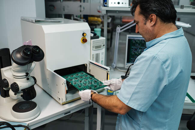 Homem introduzindo placa na máquina e microscópio — Fotografia de Stock