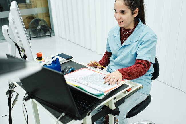 Jovem trabalhou em computador e com papel, lápis em mãos pintadas — Fotografia de Stock