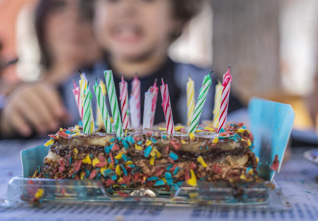 Second floor of a chocolate birthday cake. with many candles. In the background an unrecognizable child. — Stock Photo