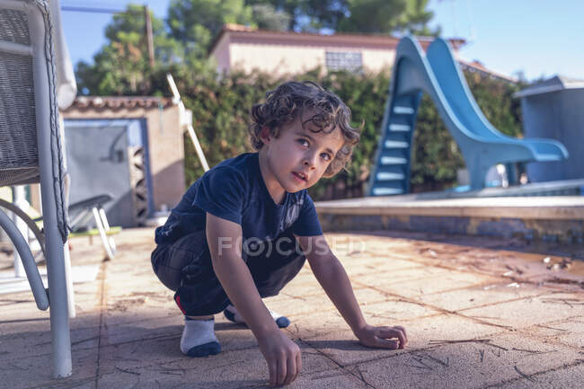 Rapaz muito jovem de 4 anos, joga no jardim de uma casa rural. — Fotografia de Stock