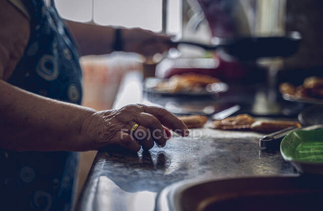 Fotos de detalhes, de uma senhora idosa, na cozinha de uma avó típica, em Espanha, enquanto ela está cozinhando. Em primeiro plano a mão com o anel de casamento, no fundo a mão segurando o — Fotografia de Stock
