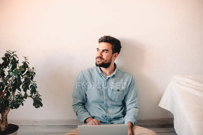 Happy businessman using laptop computer while sitting on floor — Stock Photo