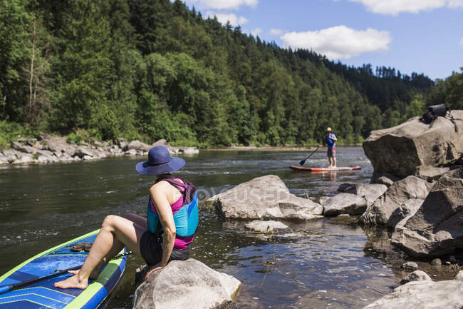 Um jovem casal aproveita o rio em seus SUPs em Oregon. — Fotografia de Stock