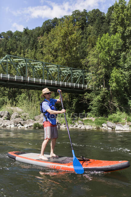Un homme aime la rivière sur sa planche à pagaie dans l'Oregon. — Photo de stock