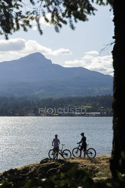Un couple profite d'une vue sur le fleuve Columbia lors d'une balade à vélo. — Photo de stock