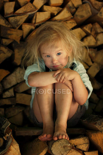 Imagen de un niño mugriento sentado en la madera. - foto de stock