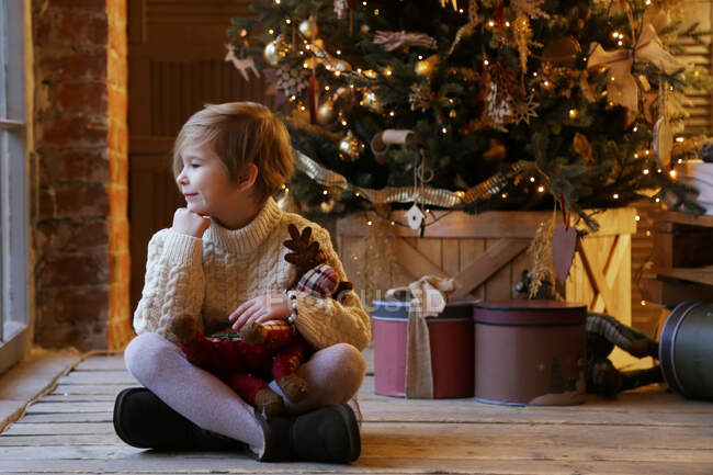 Immagine di un bambino vicino a un albero di Natale in colori caldi. — Foto stock