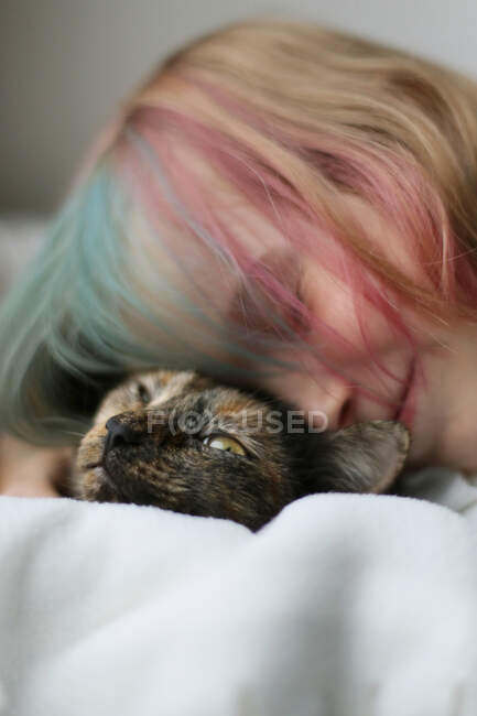 Ein Mädchen mit buntem Haar umarmt eine Katze. — Stockfoto