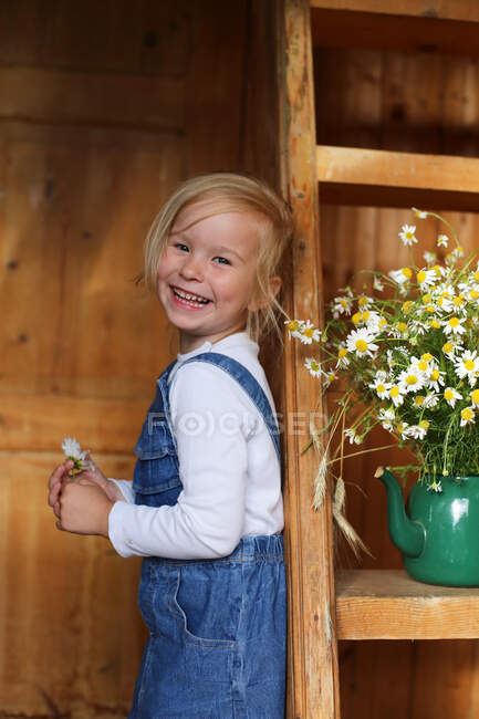Bild eines glücklichen Mädchens neben einem Strauß Gänseblümchen. — Stockfoto