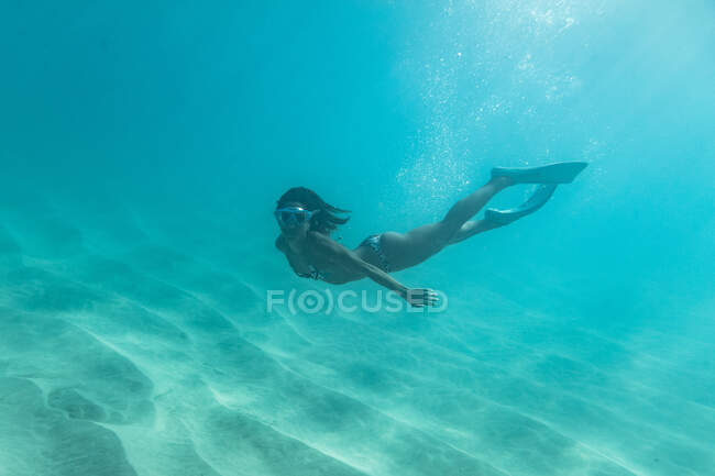 Mergulhador livre feminino nada perto do fundo arenoso do oceano de oahu — Fotografia de Stock