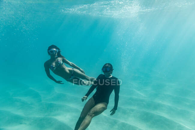 Dos mujeres conductoras libres juegan bajo la superficie del océano - foto de stock