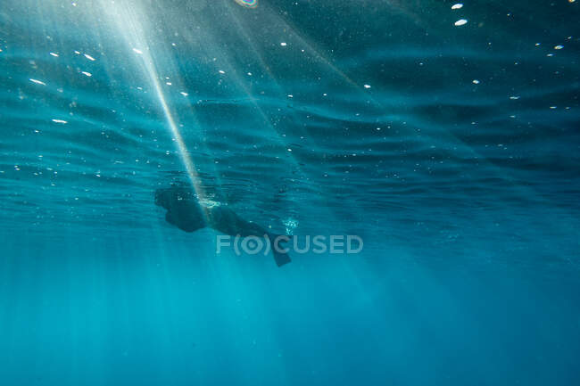 Female snorkels through light streaks at the surface of oahu ocean — Stock Photo