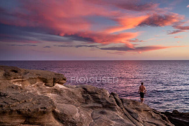 Чоловік стоїть на скелях над океаном на заході сонця на Гаваях — стокове фото