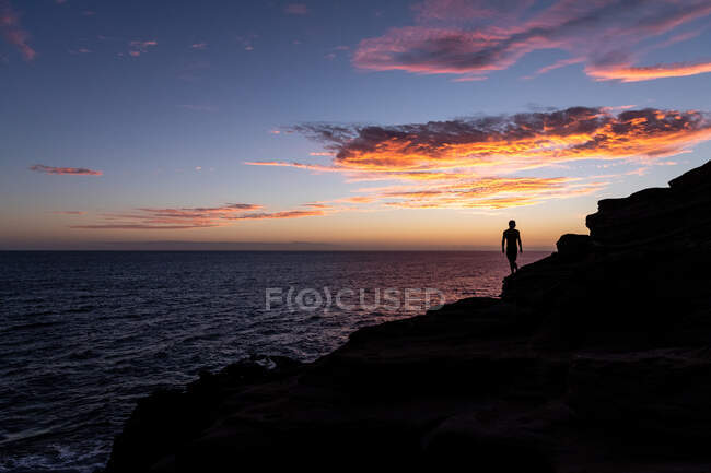 Silhueta de macho em um penhasco com pôr do sol sobre o oceano em hawaii — Fotografia de Stock