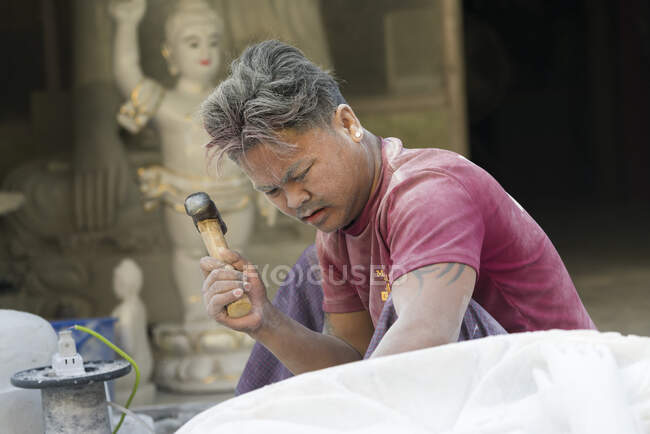 Мраморный резчик с помощью молота во время резки статуи Будды, Мандалай, Мьянма — стоковое фото