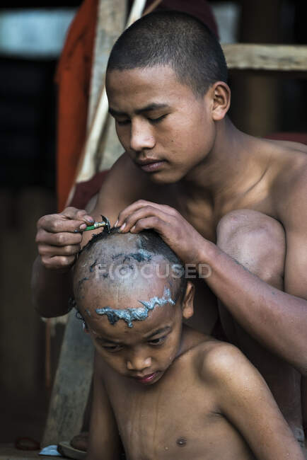 Junger Mönch rasiert Kopf eines Novizen mit Rasiermesser, in der Nähe von Hsipaw, Myanmar — Stockfoto