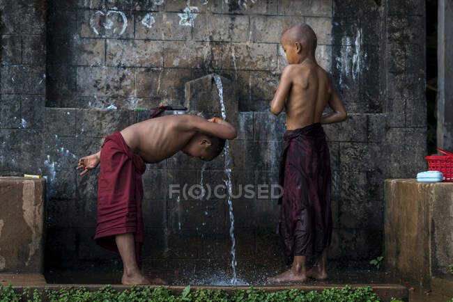 Novizenmönche waschen sich draußen unter Wasser, in der Nähe von Hsipaw, Myanmar — Stockfoto