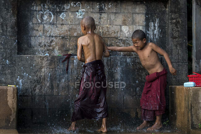 Novizenmönche waschen sich draußen unter Wasser, in der Nähe von Hsipaw, Myanmar — Stockfoto