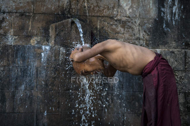 Новичок без рубашки монах купается под проточной водой на открытом воздухе, недалеко от Hsipaw, Мьянма — стоковое фото