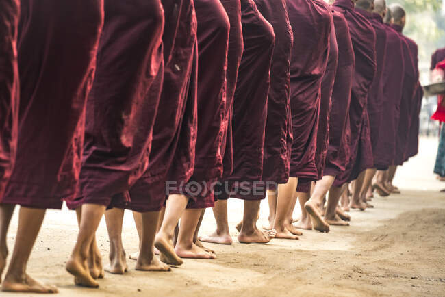 Detalle de pies de monjes esperando en fila mientras dan alm, Nyaung U, Bagan, Myanmar - foto de stock
