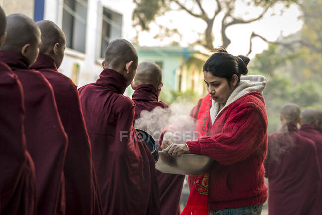 Burmese woman giving steamed rice to monks standing in line, Nyaung U, Myanmar — Stock Photo