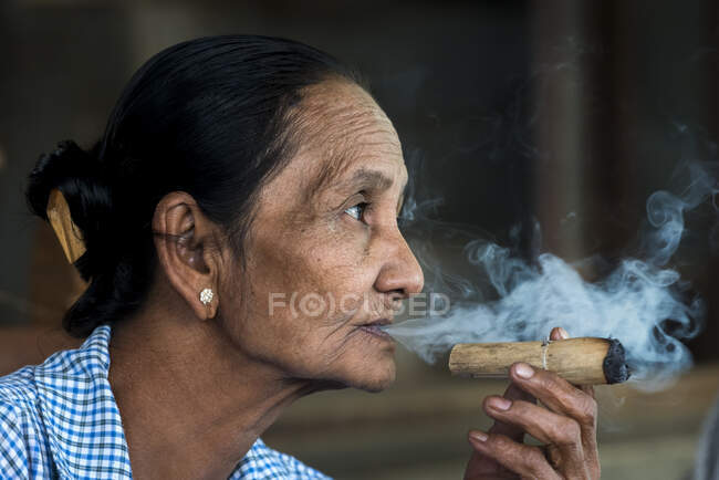 Бирманская женщина курит толстую бирманскую соломенную сигару, Баган, Мьянма — стоковое фото