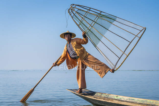 Intha pescador posando con red de pesca cónica típica en barco, Lago Inle, Nyaungshwe, Myanmar - foto de stock