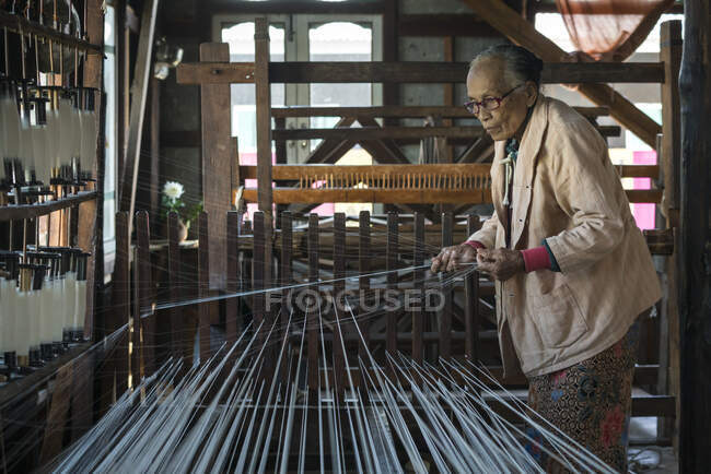 Donna birmana anziana che prepara i fili per lavorare sul telaio, Lake Inle, Myanmar — Foto stock