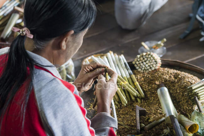 Mains de femme fabriquant et roulant des cigares birmans à l'atelier de fabrication de cigares de ceroot, lac Inle, Myanmar — Photo de stock