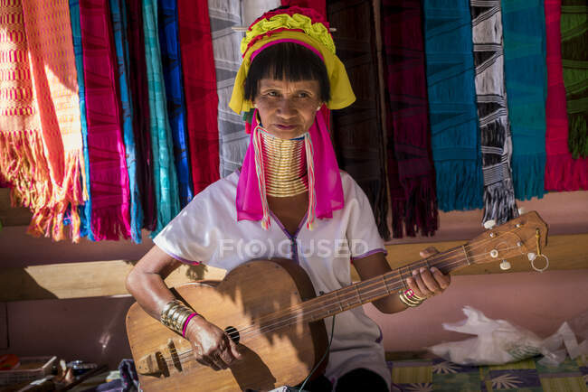 Старша бірманка з племені Каян (AKA Padaung, довга шия) грає на музичному інструменті, схожому на гітару, біля Лойкау, штат Кая, М'янма. — стокове фото