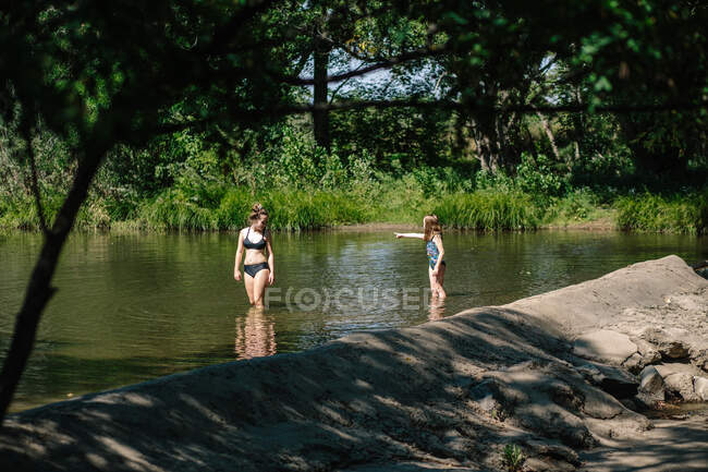 Due ragazze in piedi e giocare in un piccolo fiume in una giornata di sole — Foto stock