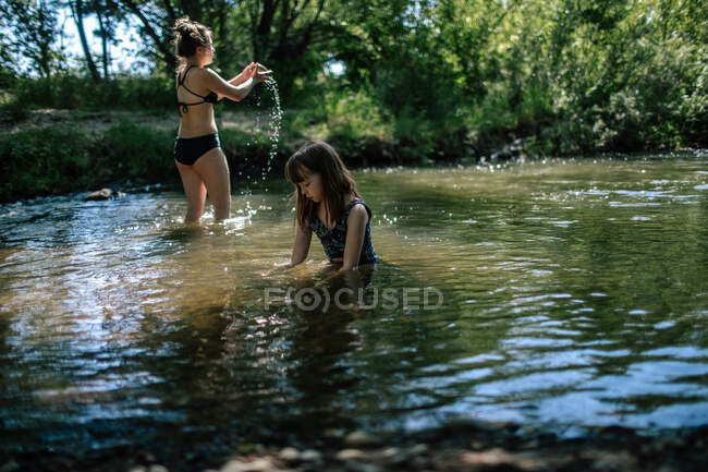 Zwei Mädchen spielen an einem Sommertag in einem flachen Bach — Stockfoto