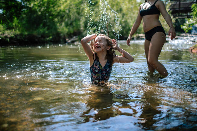 Jovem feliz salpicando em um riacho em um dia quente — Fotografia de Stock