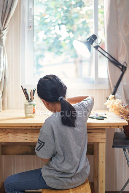 Vista rara de uma menina trabalhando na mesa de madeira — Fotografia de Stock